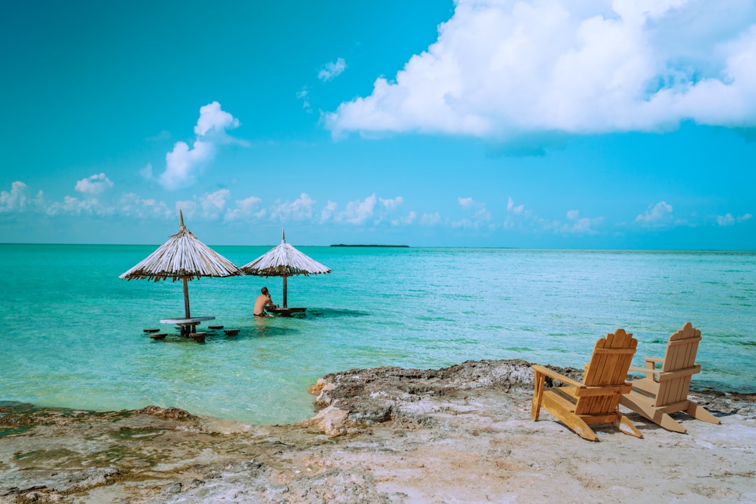 Photo by Meritt Thomas brown wooden lounge chairs on beach during daytime