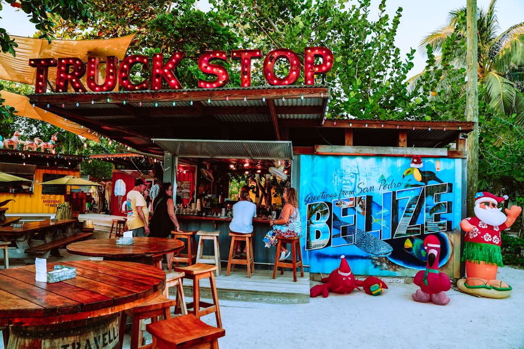 Photo by Meritt Thomas people sitting on brown wooden chairs near red and blue store during daytime